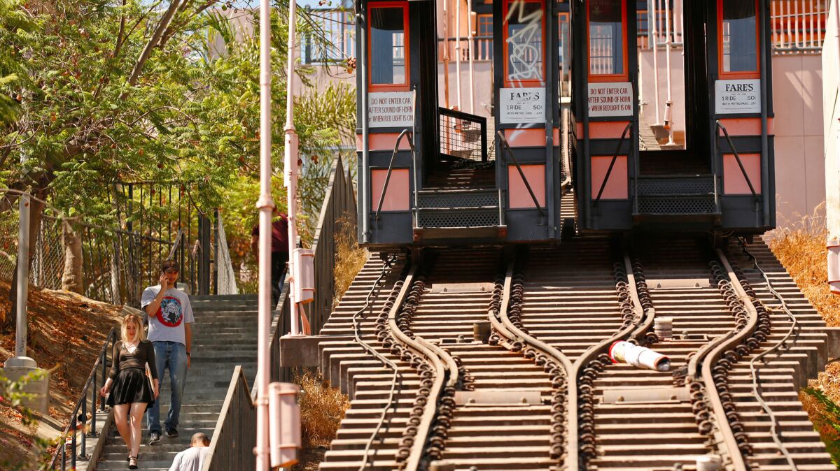 Pedestrians walk down the 153 steps of the stairway parallel to Angels Flight, now covered in graffiti.