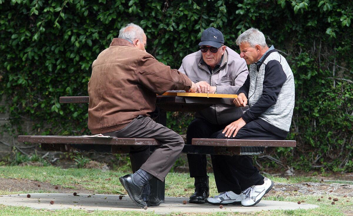 Three men sit at a tabe at Wilson Mini Park in Glendale on Wednesday, March 30, 2016.