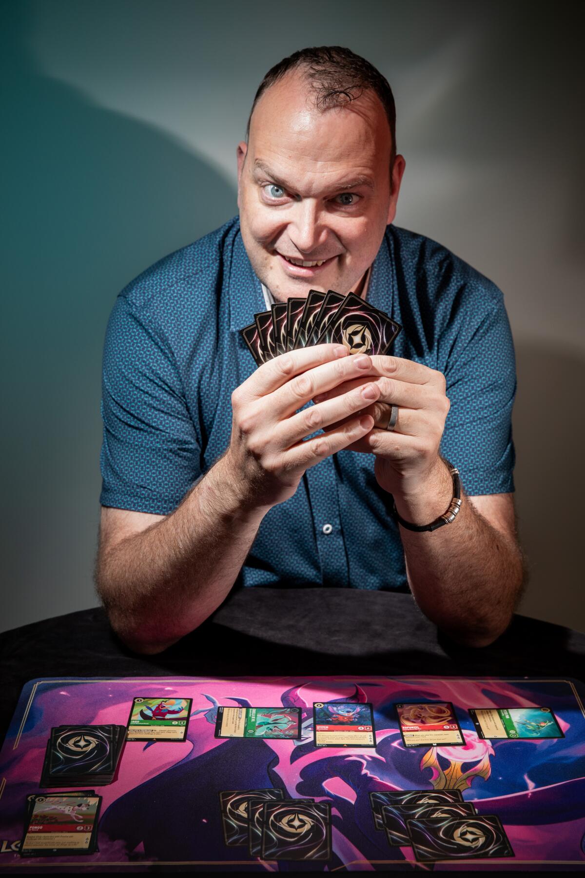 A man holds trading cards fanned out in his hands at a table spread with more cards