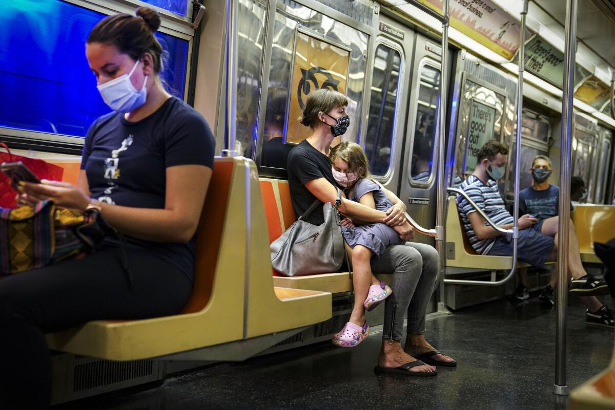 FILE — New York City subway passengers wear protective masks due to COVID-19 concerns, Aug. 17, 2020. New York state is dropping its mask requirement on public transportation thanks in part to the availability of new booster shots targeting the most common strain of COVID-19, Gov. Kathy Hochul announced Wednesday, Sept. 7, 2022. (AP Photo/John Minchillo, File)
