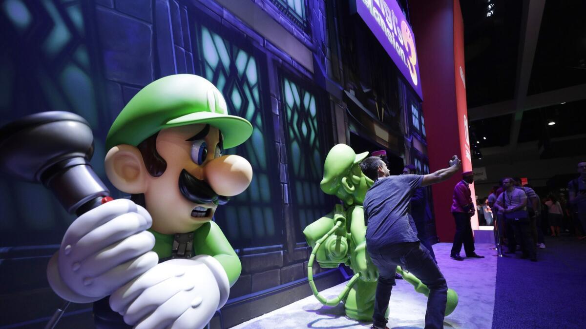 An attendee takes a picture in front of "Luigi's Mansion 3" during the 2019 E3.