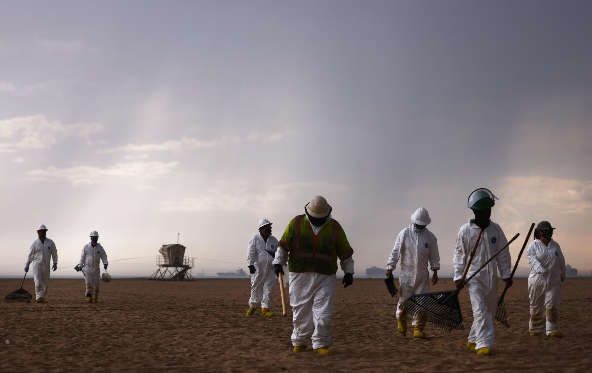 Cleanup workers in protective suits at  Huntington State Beach. 