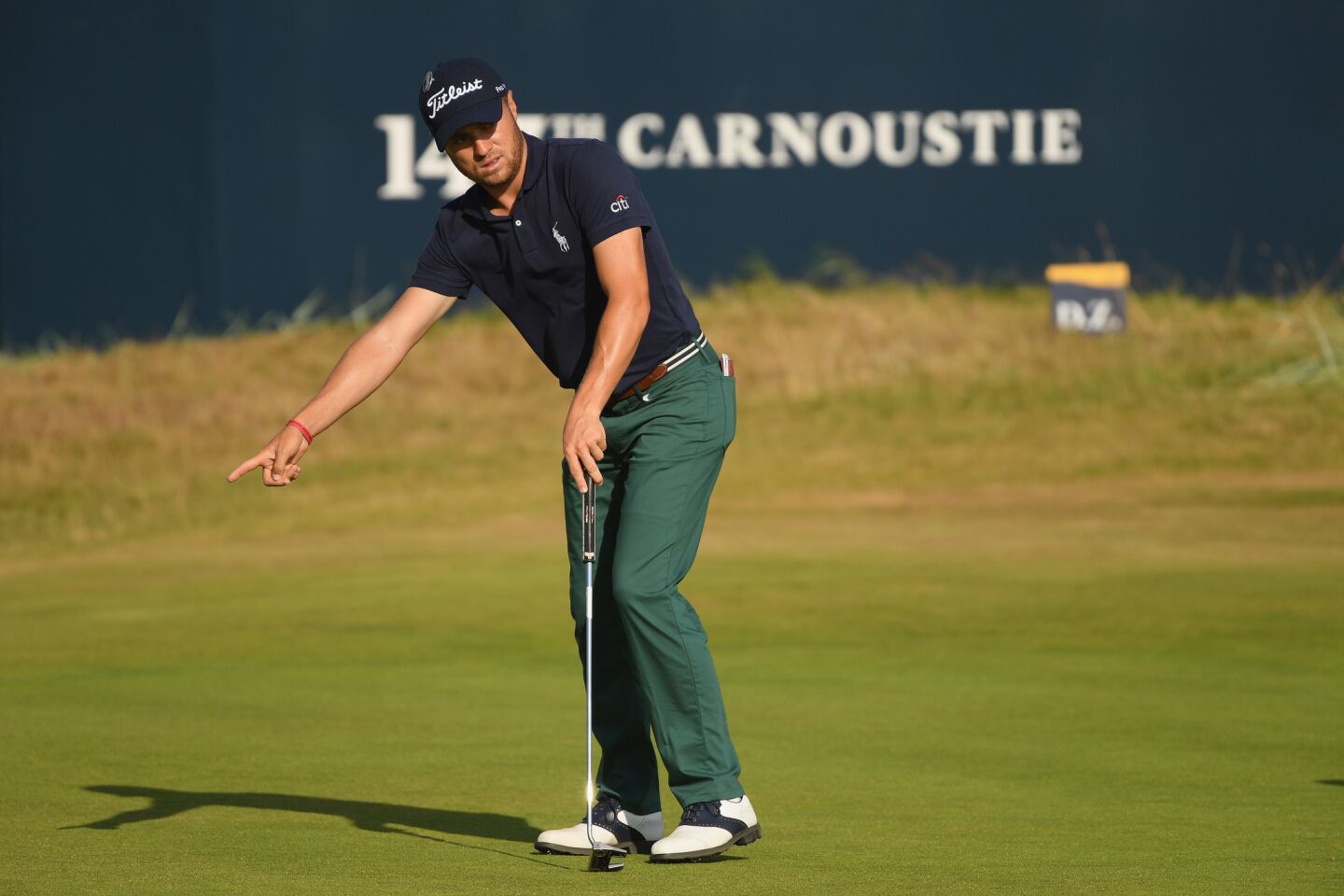 Justin Thomas of the United States indicates where his ball should go after putting on the 18th green on Day 1 of the British Open.