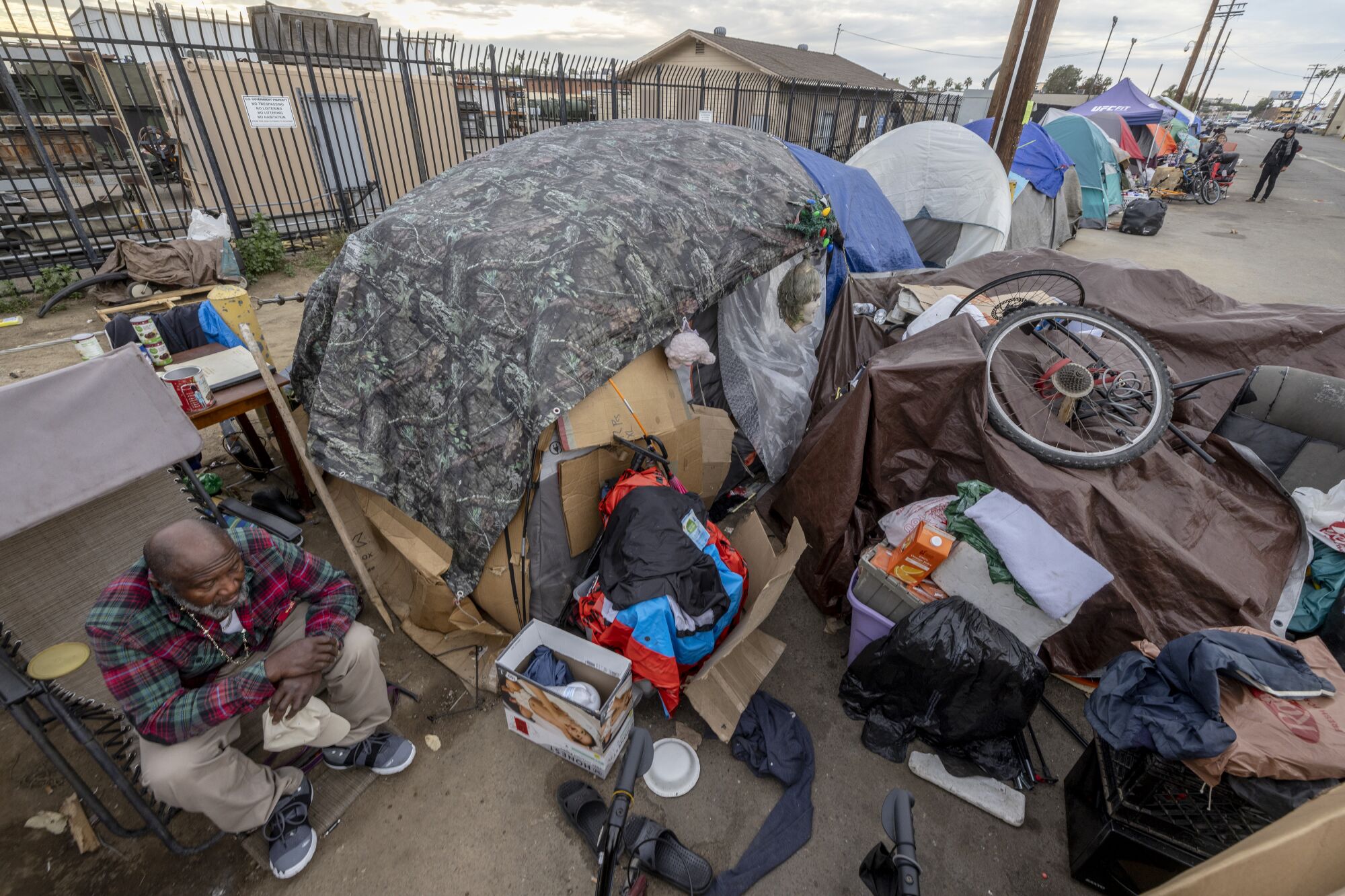 A 61-year-old homeless man sits next to his tent at a homeless encampment on Sports Arena Boulevard in San Diego.