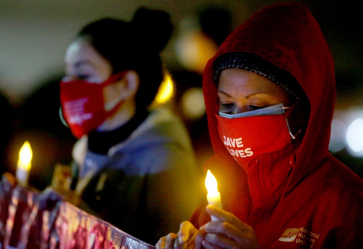 Registered nurses in masks hold a candlelight vigil.