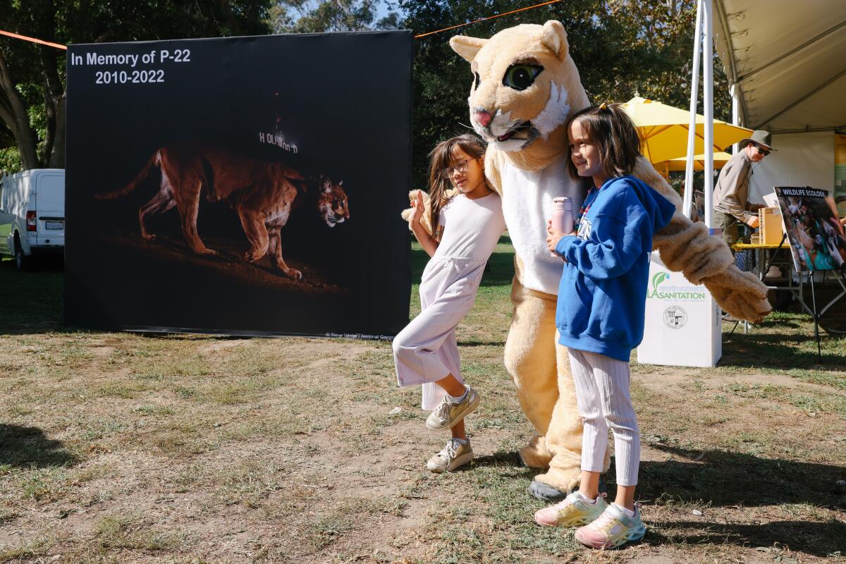 Two children pose with a person in a mountain lion costume.