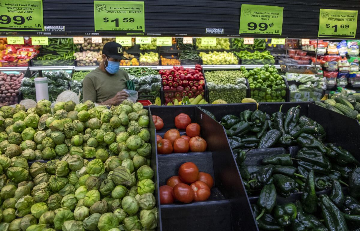 A shopper wears a mask to guard against the coronavirus as he picks out produce items at the Advance Food Market on Saturday, April 4, 2020 in West Adams, CA.