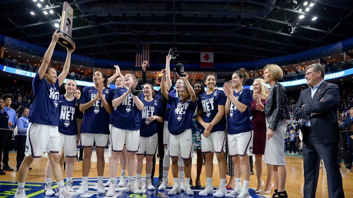 Connecticut's Saniya Chong holds the trophy as she poses with her teammates following their 90-52 win over Oregon in a regional final game in the NCAA women's college basketball tournament on Monday.