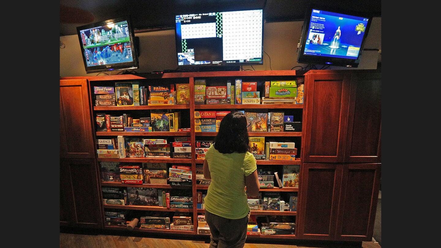 Kayla Campato, of Bakersfield, considers other game options at Guild Hall in Burbank on Thursday, September 14, 2017. Guild Hall is Burbank's first esports bar, open for 6 weeks, where they stream various live video game gameplay instead of conventional sports, and have a wall of choices for board games.