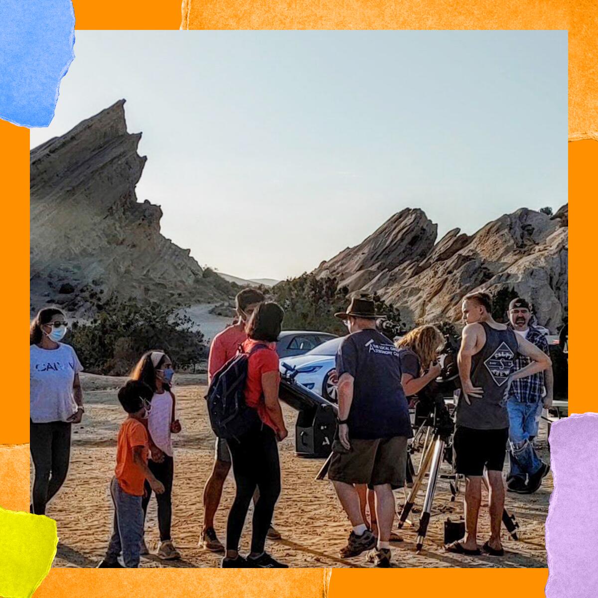 People stand in a group in front of a sawtooth rock formation.