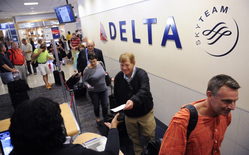 Delta Air Lines passengers board a flight at Hartsfield-Jackson Atlanta International Airport. Critics say the carrier is shaming passengers into upgrading their basic economy fare ticket.