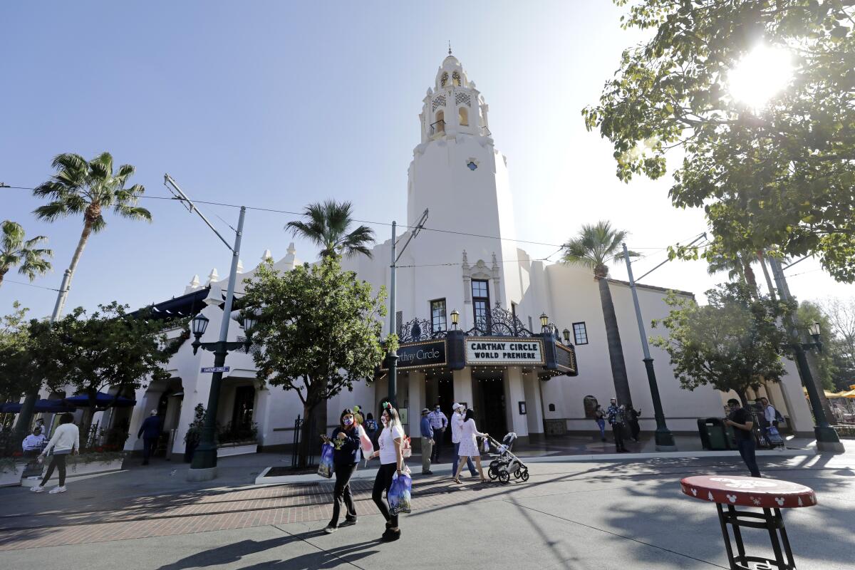 Visitors in masks walk the streets of Disney California Adventure.