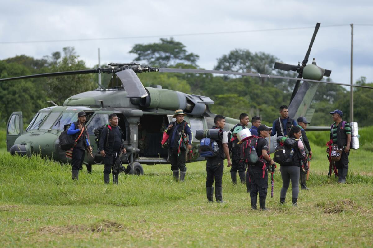 Hombres indígenas esperan para abordar un helicóptero