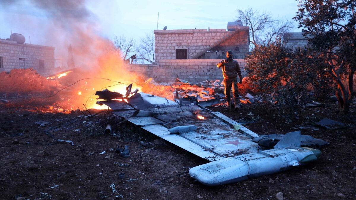 A rebel fighter takes a photograph of a downed Russian fighter jet in Syria's northwest province of Idlib on Feb. 3, 2018.