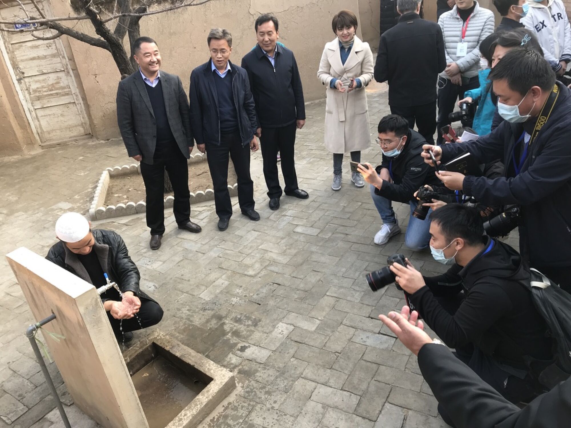 Inside a village museum honoring Xi Jinping's visit to Bulengou in 2013, a Dongxiang man washed his hands in running water.