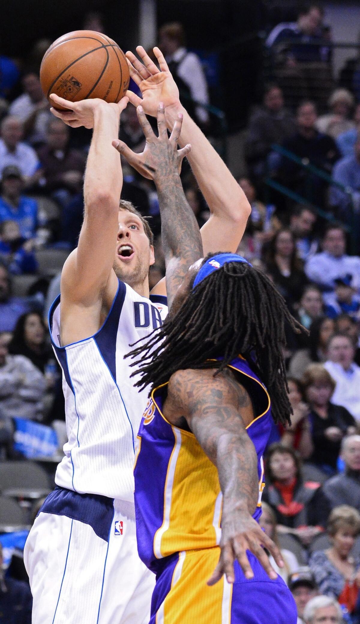 Dallas Mavericks forward Dirk Nowitzki, left, tries to shoot over Lakers center Jordan Hill during a game at the American Airlines Center in Dallas.