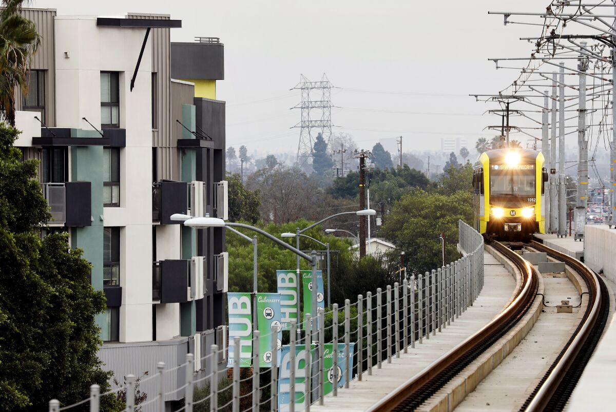 A light-rail train passes an apartment building.