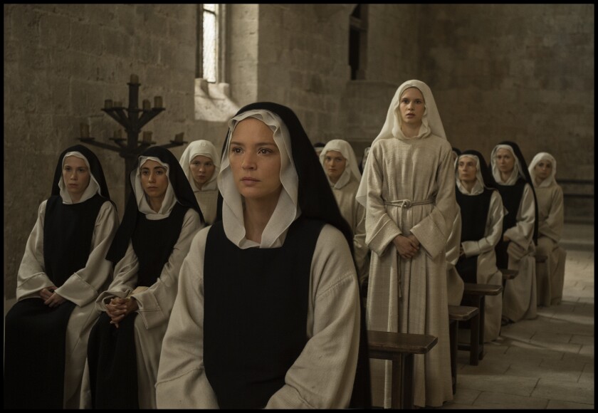 This image released by IFC Films shows Daphne Patakia, standing background, and Virginie Efira in a scene from "Benedetta." (IFC Films via AP)
