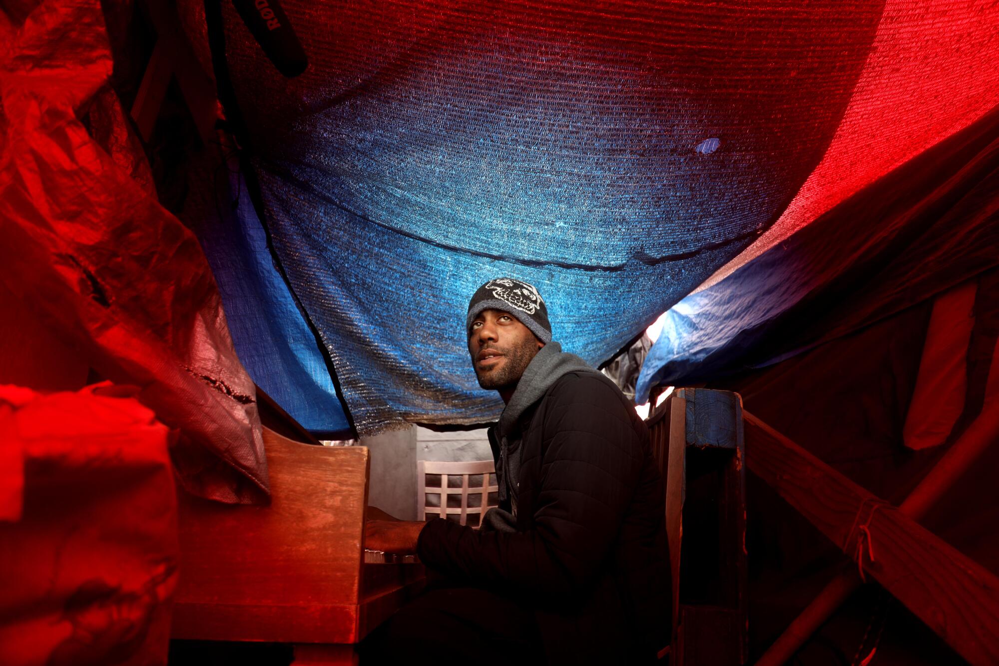 A man plays his piano inside his tent.