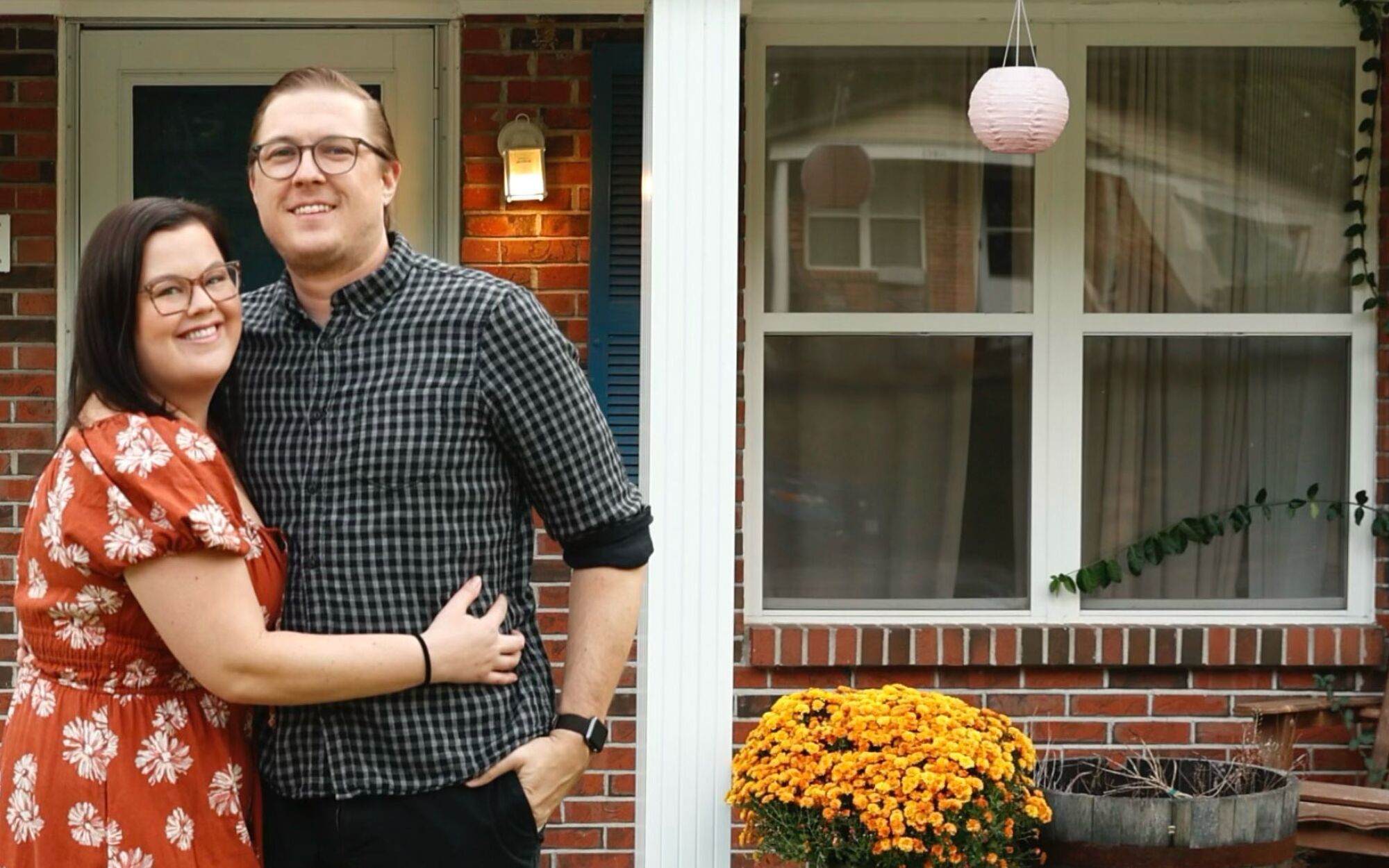 A woman and a man stand outside the house
