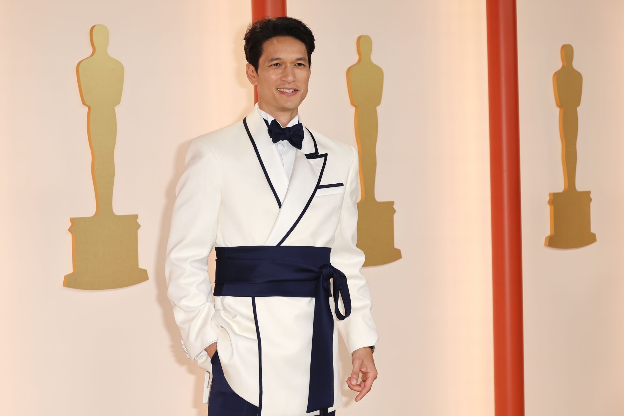 Harry Shum Jr. in a white tux with black collar trim and black sash.