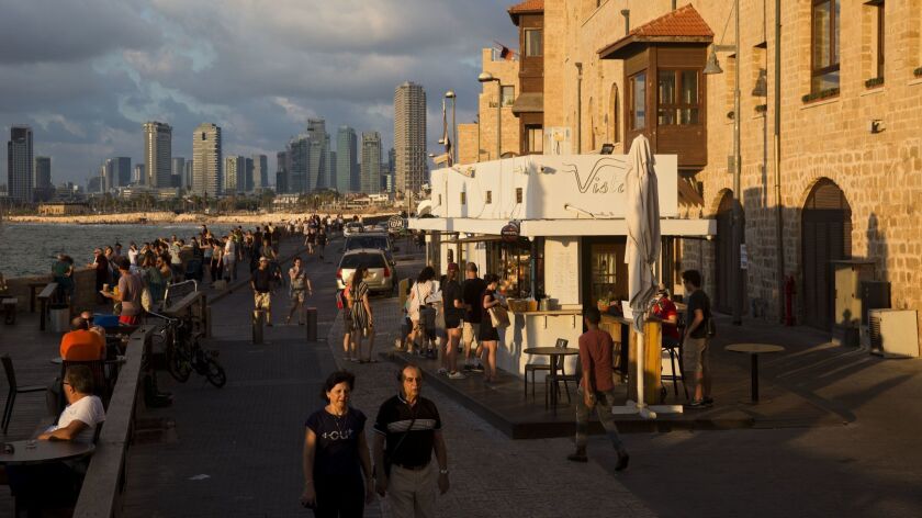 People walk along Jaffa's promenade overlooking Tel Aviv's skyline and the Mediterranean sea in Jaffa, Israel on July 28, 2018.
