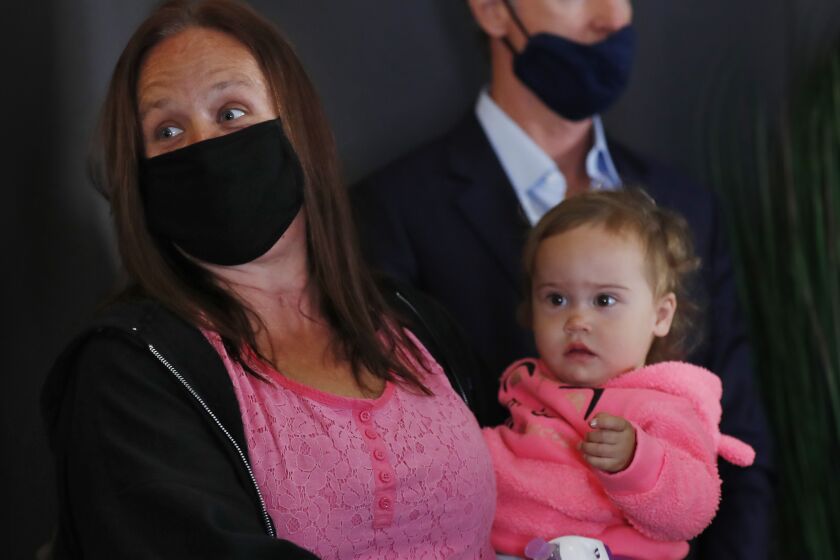 SAN DIEGO, CA - MAY 11: Lindsey Prescott and her daughter Mia Grace, along with Governor Gavin Newsom wait for a news conference about a $12 billion package bolstering the state's response to the homelessness crisis at the Kearney Vista Apartments, which houses homeless people in a converted hotel on Tuesday, May 11, 2021 in San Diego, CA. Prescott is a resident at the complex. (K.C. Alfred / The San Diego Union-Tribune)