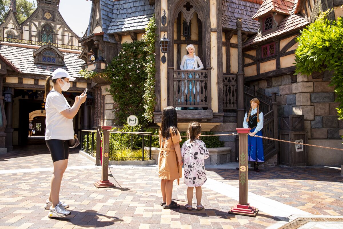A family takes pictures with Elsa and Anna characters at Disneyland.