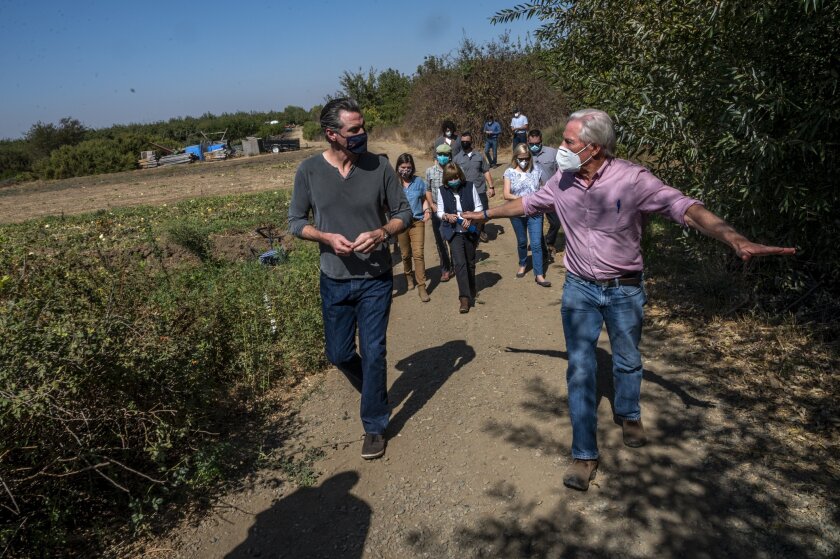 A group of people in masks walk on a dirt trail