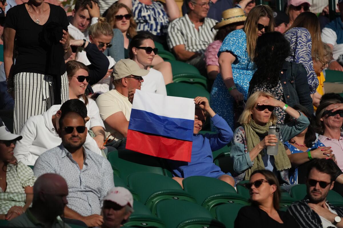 A spectator holding a Russian flag watches  the men's singles match between Daniil Medvedev and Marin Cilic.