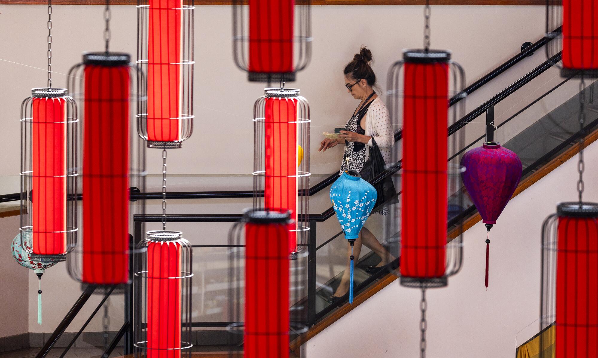 A woman walks down a flight of stairs while red lanterns hang in the foreground.