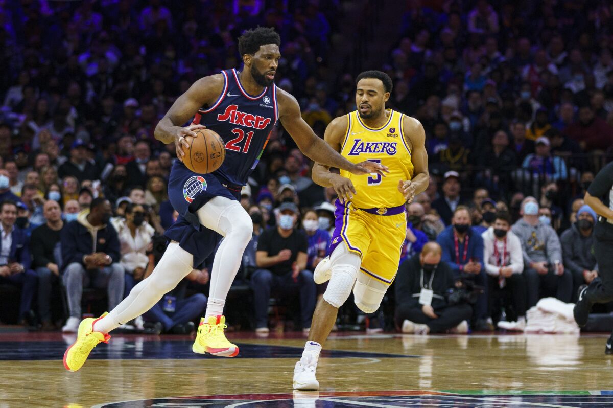Philadelphia 76ers' Joel Embiid drives upcourt with Lakers' Talen Horton-Tucker defending.