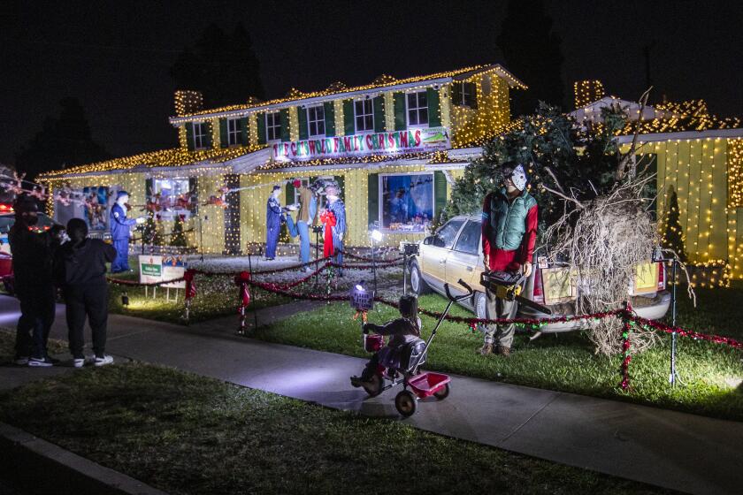 La Mirada, CA - December 10: Neighbor Aria Sadler, 4, views Jeff Norton's house in La Mirada, made up to look like the house from National Lampoon's Christmas Vacation movie. The owner put up a fake second story on his home, to make it just the like one in the movie, but the city of La Mirada fined him for it. He refused to take it down and now the city has relented. Photo taken in La Mirada, CA on Friday, Dec. 10, 2021. (Allen J. Schaben / Los Angeles Times)