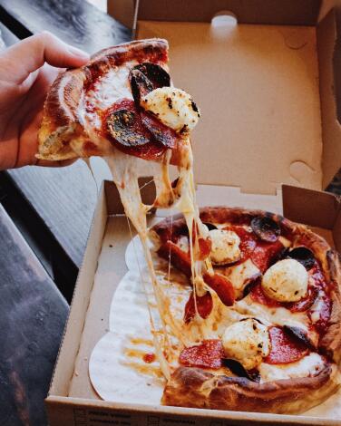 A vertical pic of a hand pulling a slice of pepperoni-and-ricotta-topped deep-dish pizza at fast-casual chain Fresh Brothers.