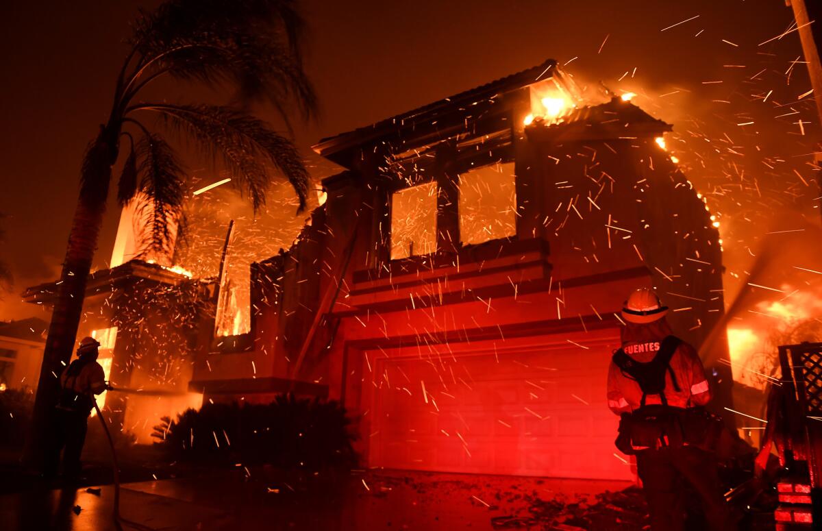 Firefighters battle a house fire on Churchwood Drive as the Woolsey Fire burns in the Oak Park neighborhood.