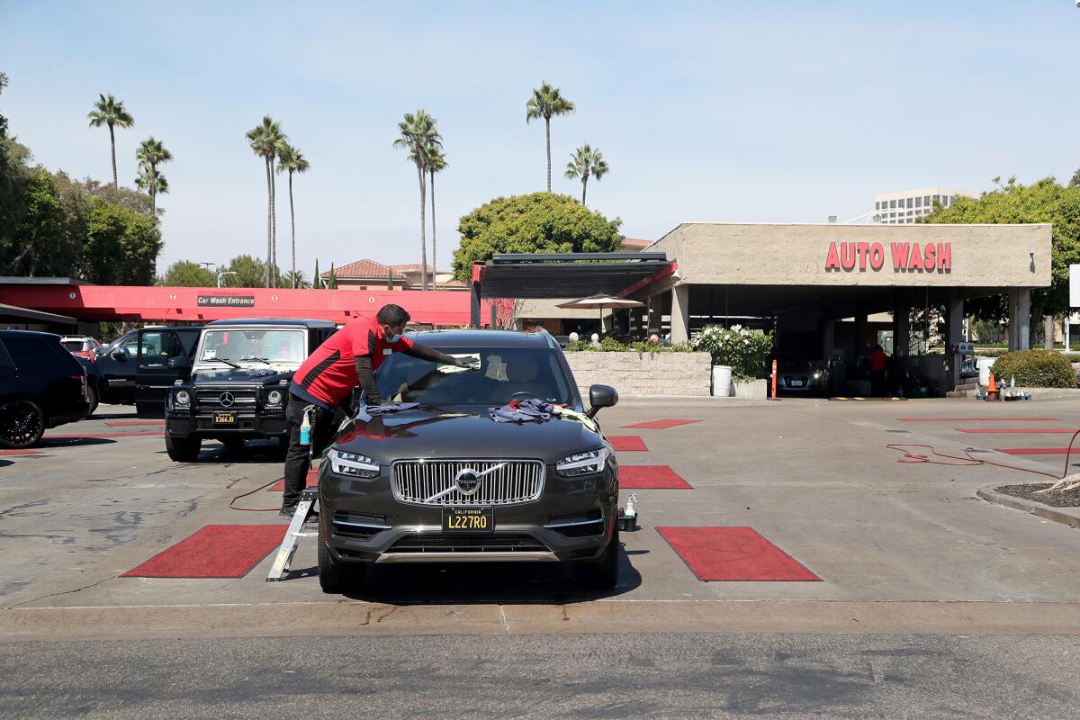 A worker wipes down a vehicle at Newport Beach Car Wash on Thursday.