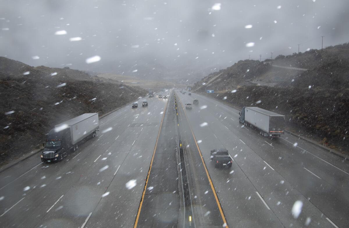 Vehicles on the 5 Freeway drive through snow in Gorman.