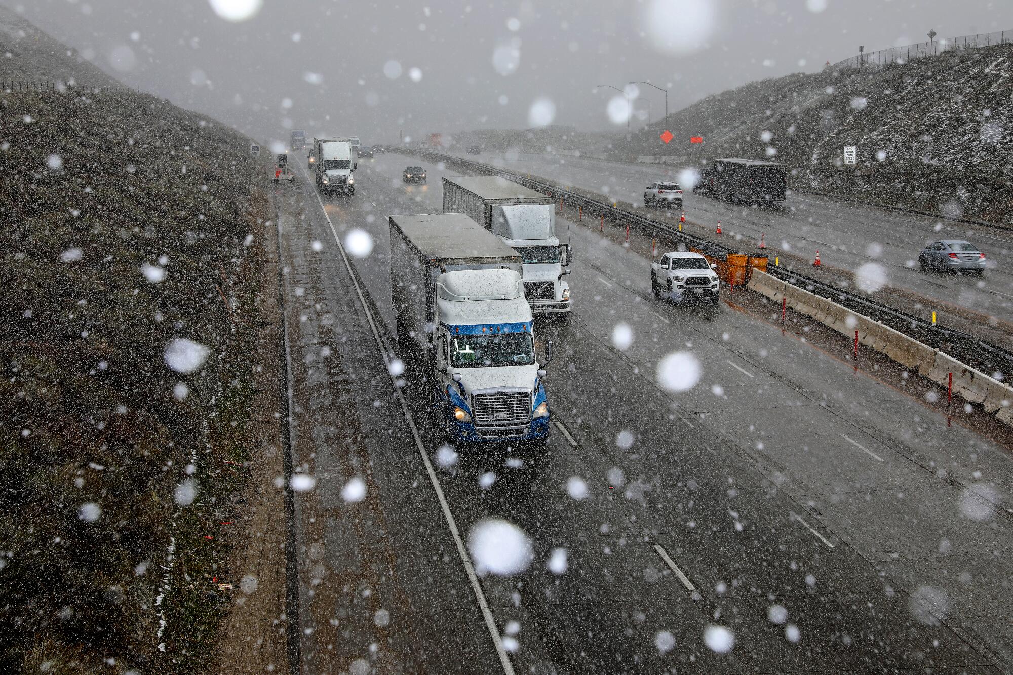 Snow falls on vehicles on a freeway