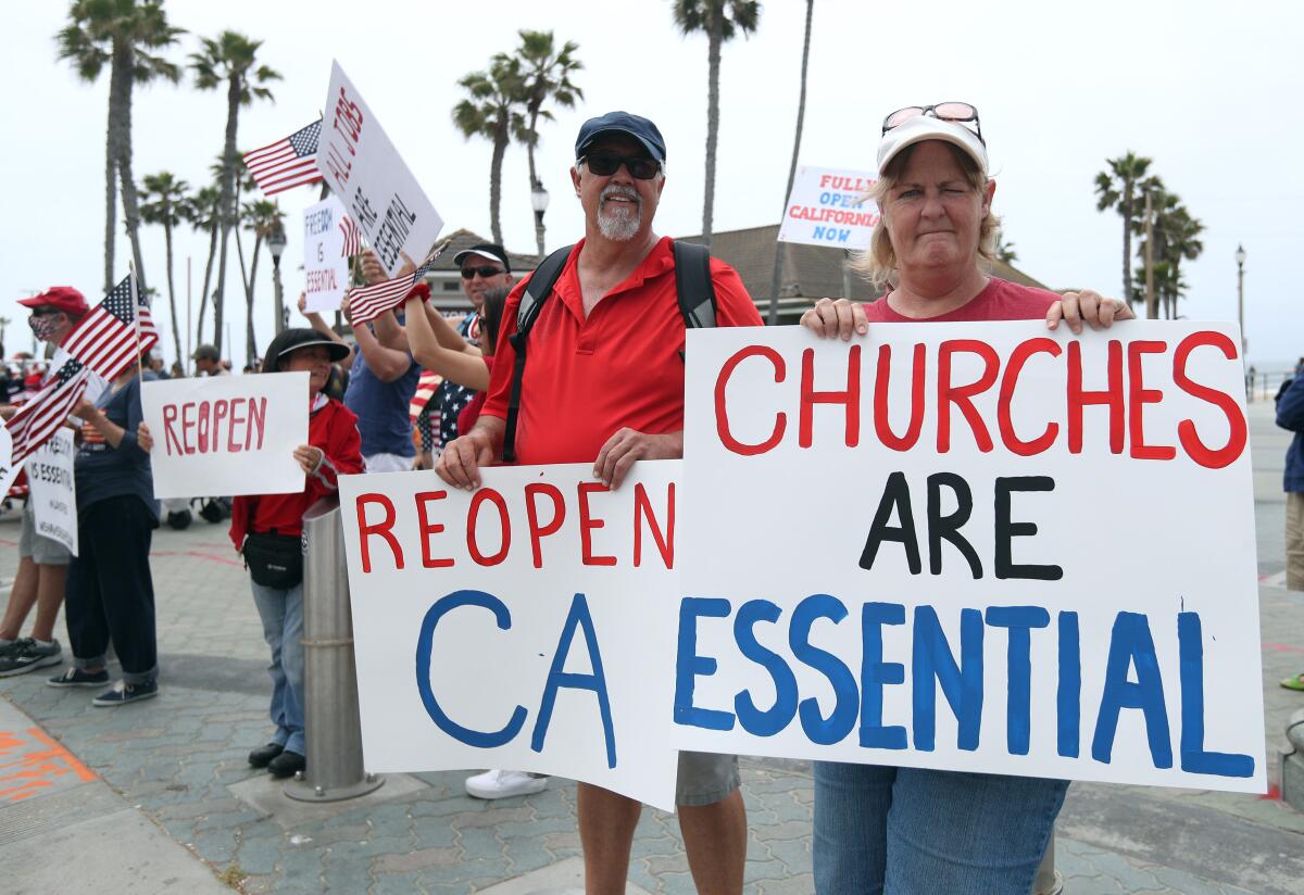 Wally Thomas de Lake Forest, centro, y Denean MacAndrew de Mission Viejo protestan el sábado en Pier Plaza en Huntington Beach.