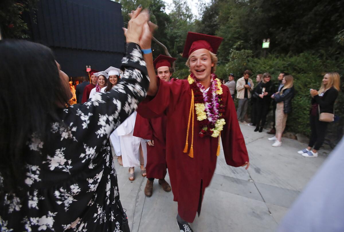 Summa Cum Laude graduate George Knapp, right, greets attendance administrator Connie Byrnes, as he enters the Irvine Bowl during the Laguna Beach High School commencement ceremony in 2019. The district intends to hold an event to honor seniors later in the summer.