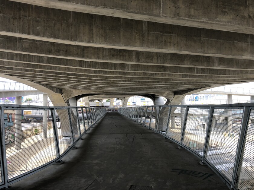 The ribbed concrete underside of the 6th Street Bridge is visible from a gently sloping ramp underneath the deck