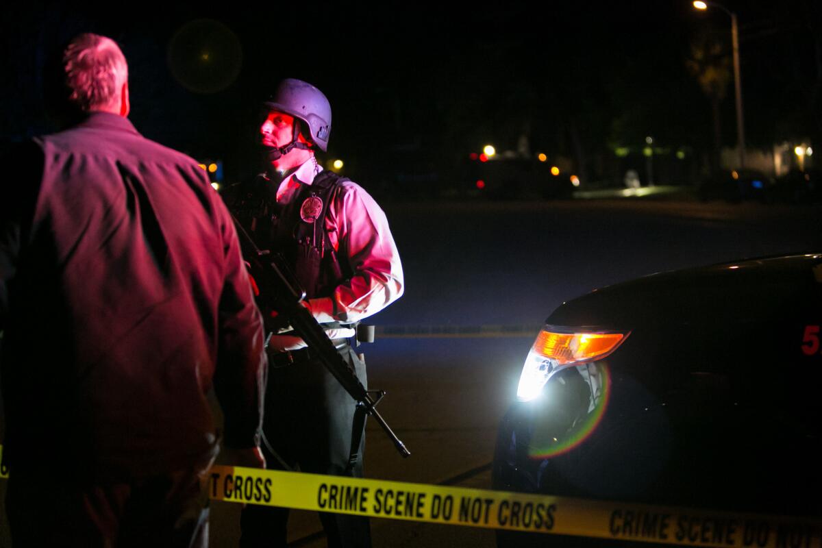 Law enforcement stands guard at a police line as investigators work at a Redlands home after the San Bernardino attack.