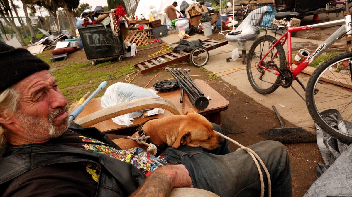 In this January 2017 file photo, Joe Sigler 59, sits with his dog Mojo as his homeless encampment along W. 95th Street in the Manchester Square neighborhood of Los Angeles.