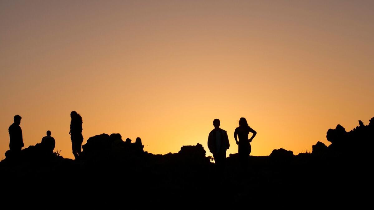 Visitors to Corona del Mar State Beach hike the rocks to see the sunset.