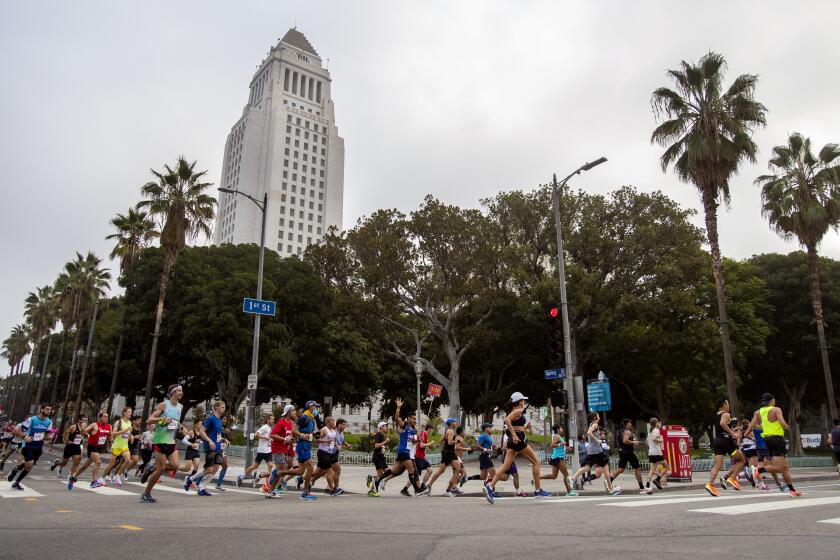 LOS ANGELES, CA - NOVEMBER 7, 2021: Runners make the turn onto 1st Street near City Hall at the 3-mile mark during the LA Marathon on November 7, 20201 in Los Angeles, California. (Gina Ferazzi / Los Angeles Times)