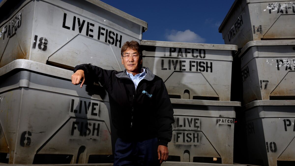 Young Kang, an executive at Vernon-based Pacific American Fish Co., is shown with the company's containers of live fish.
