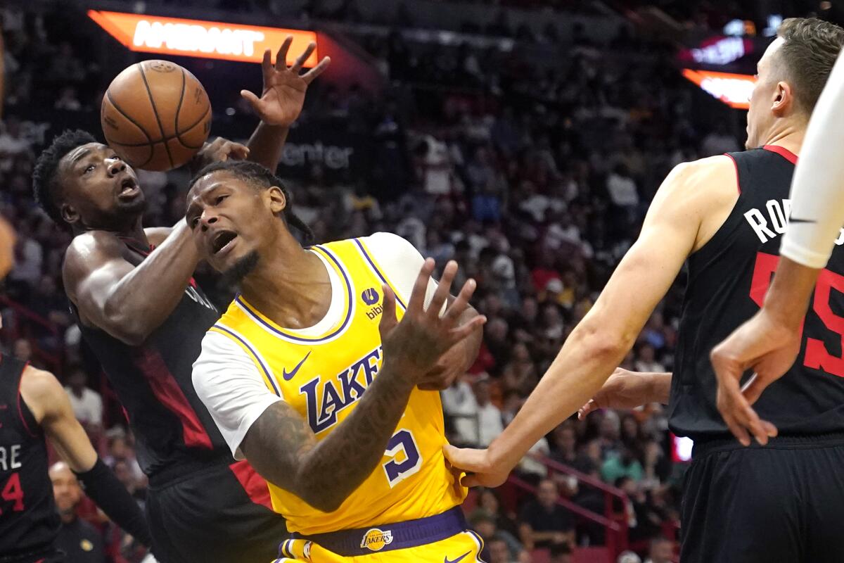 Lakers forward Cam Reddish, center, is fouled by Miami Heat center Thomas Bryant, left, during the first half Monday.