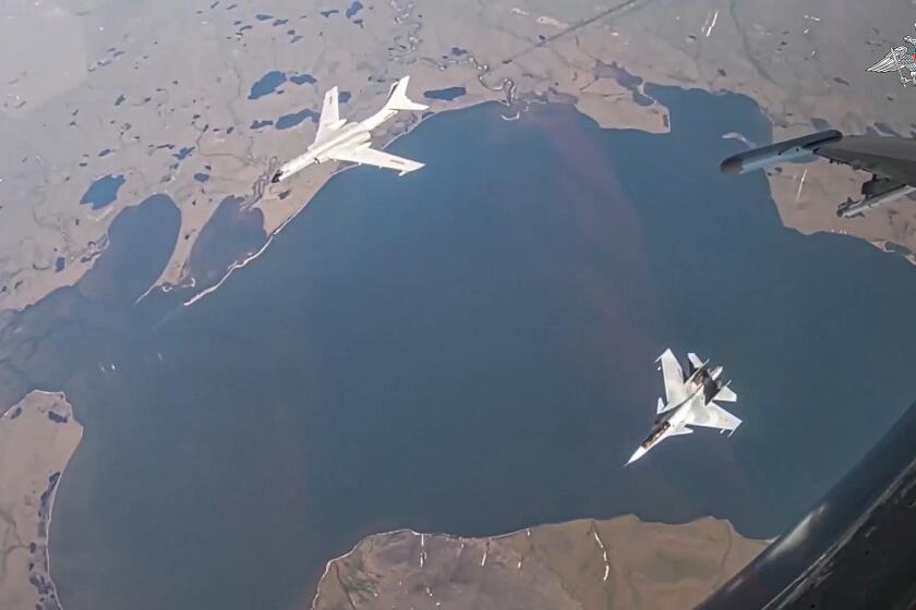 In this photo taken from video released by Russian Defense Ministry Press Service on Thursday, July 25, 2024, A H-6K long-range bomber of the Chinese air force, upper left, is seen escorted by a Su-30 fighter of the Russian air force during a joint Russia-China air patrol. (Russian Defense Ministry Press Service via AP)
