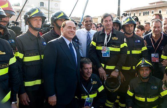President Barack Obama, center, and Italian Prime Minister Silvio Berlusconi pose with local firefighters while touring earthquake damage in the city center of L'Aquila during the Group of 8 summit.