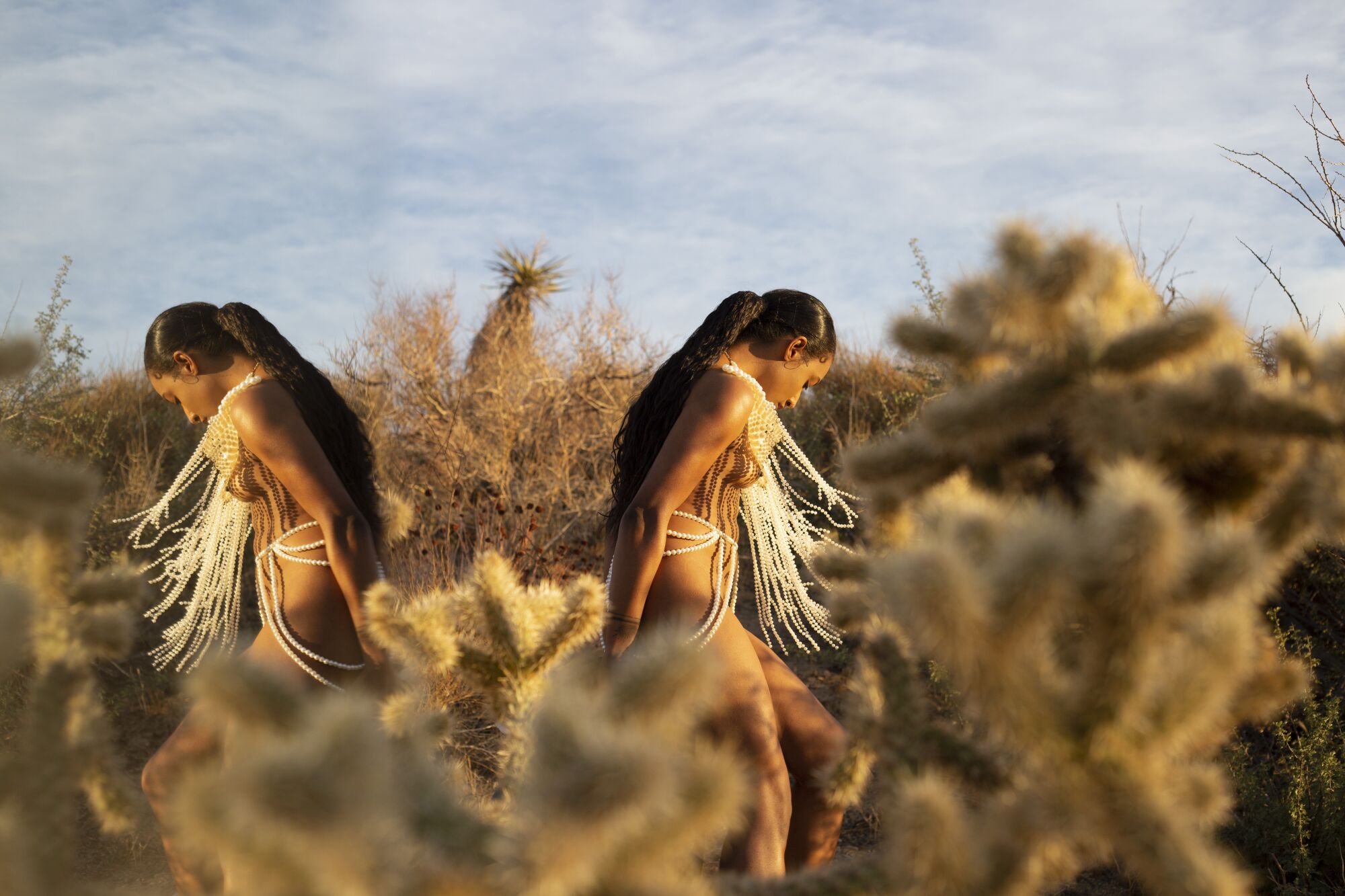 A double exposure of a scantily clad woman back to back with herself in the desert.